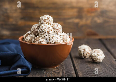 Energie Kugeln von Nüssen, Hafer und Termine in eine braune Schale closeup auf Holz- Hintergrund mit Copyspace. Gesundes Essen. Raw Dessert. Stockfoto