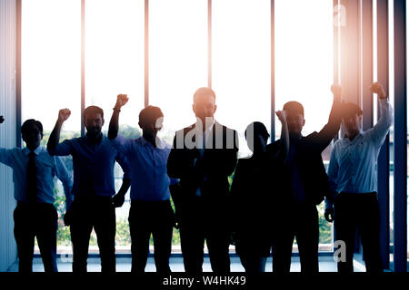 Silhouetten von Kollegen und Vorgesetzten Erfolg feiern gemeinsam beim Stehen in der Nähe der Fenster im Büro Stockfoto