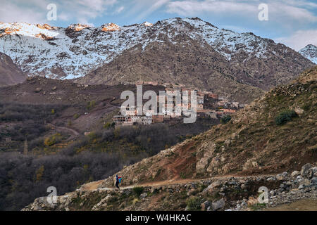 Ein Blick auf den Sonnenuntergang und den touristischen Weg in ländlichen Berg Dorf im Hohen Atlas Marokko Afrika mit schneebedeckten Gipfeln Stockfoto