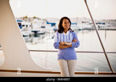 Reife Frau, glücklich, als sie auf einem Schiffsdeck steht Stockfoto