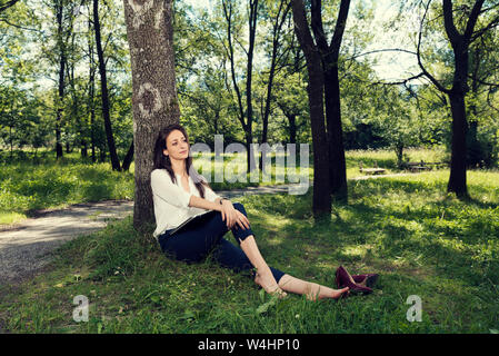 Business woman ruhend Sitzen unter den Baum ohne Schuhe in einem öffentlichen Park selektiven Fokus Stockfoto