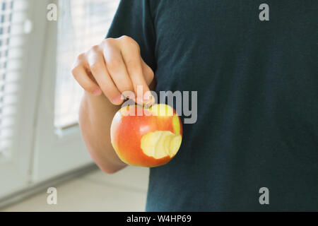 Ein junger Mann hält einen gebissen Apple in seinen Händen. Stockfoto