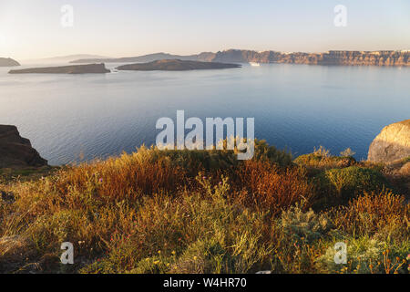 Panoramablick auf die einzigartige Meerblick zur Vulkaninsel Nea Kameni, die Caldera, Fira und Oia, kurz vor Sonnenuntergang, Santorin, Thira, Griechenland Stockfoto