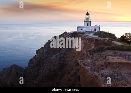 Klippen und Leuchtturm bei Sonnenuntergang in Akrotiri, Santorini, Griechenland. Stockfoto