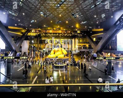 Im Bereich der Hamad International Airport, mit den riesigen gelben Teddybär Statue in der Mitte und Passagiere gehen, nachts. Stockfoto