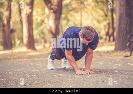 Jungen athletischen Mann tun Push-ups im Park, Vorbereiten für Morgen Workout. Stockfoto