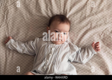 Süßes neugeborenes Mädchen auf dem Bett liegen. Das Baby will im Bett der Eltern schlafen. Stockfoto