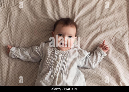 Süßes neugeborenes Mädchen auf dem Bett liegen. Das Baby will im Bett der Eltern schlafen. Stockfoto