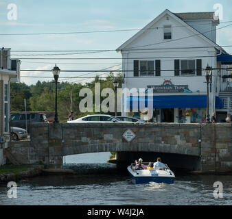 Main Street, Suceava, New Hampshire, am Lake Winnipesaukee. Eine kleine Power Boat fließt durch einen Kanal unter der Main Street. Stockfoto