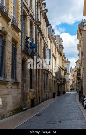 Bordeaux, Frankreich - 5. Mai 2019: Mannequin einer schwarzen Katze und ein Mann auf dem Balkon eines Wohnhauses im historischen Zentrum von Bordeaux, Frankreich Stockfoto