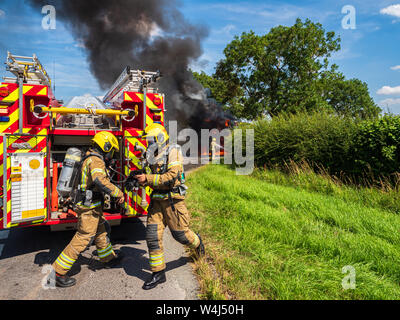 Feuerwehrleute aus Lincolnshire Fire and Rescue tragen Atemschutzgeräte in Aktion am Ort der großen Fahrzeug Feuer mit einem Mähdrescher Stockfoto