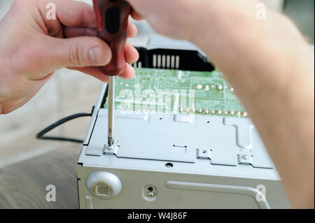 Ein Mann wird mit einem Schraubendreher die Musik System zu öffnen. Stockfoto