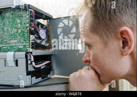 Ein Mann ist die Instandsetzung der musikalischen System. Er ist auf der Suche innerhalb des Gerätes. Stockfoto