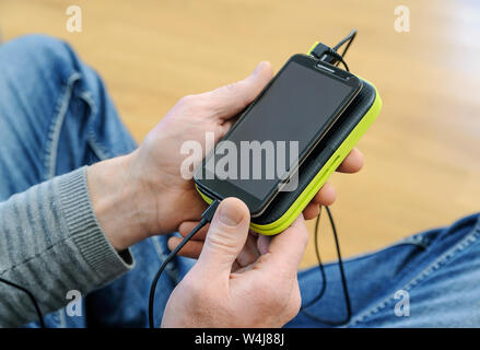 Ein Mann hält ein Smartphone und eine Bank. Stockfoto