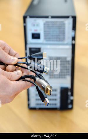 Es gibt verschiedene Kabel, Stecker in den Händen eines Mannes. Stockfoto