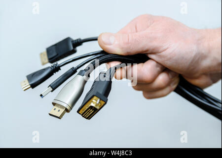 Es gibt verschiedene Kabel und Stecker in der Hand eines Mannes. Stockfoto