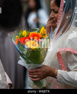 SHEFFIELD, UK - 20. Juli 2019: Die Mutter der Braut hält einige schöne helle orange und gelbe Blumen in der Hand nach einer Hochzeit Stockfoto