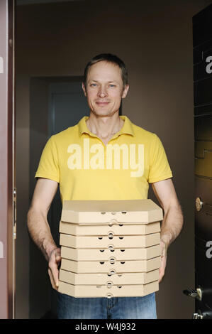 Essen Home. Der Mann hält Boxen mit Pizza in der Tür. Stockfoto