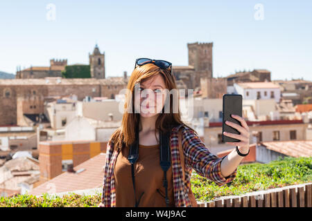 Eine junge Rothaarige touristische macht einen selfie aus der Sicht der Galarza mit der Altstadt von Caceres im Hintergrund Stockfoto