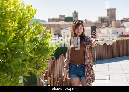 Eine junge Rothaarige touristische macht einen selfie aus der Sicht der Galarza mit der Altstadt von Caceres im Hintergrund Stockfoto