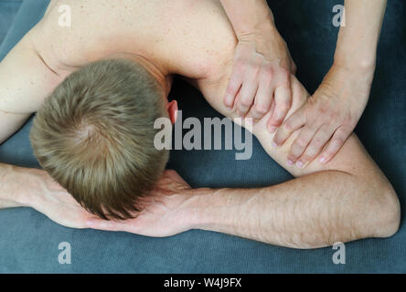 Gesundheit Massage Therapie. Weibliche Hände massieren Arm des Mannes. Stockfoto