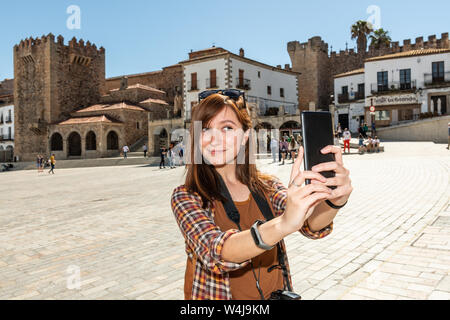 Eine junge Rothaarige touristische nimmt eine selfie auf der Plaza Mayor de Caceres Stockfoto