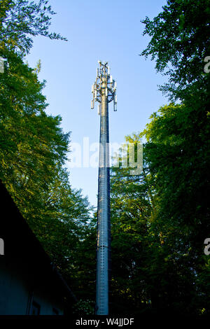 Telekommunikation Mast und grüne Bäume am blauen Himmel Stockfoto