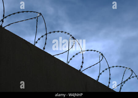 Silhouette von Concertina wire Perimeter an einer Wand Stockfoto