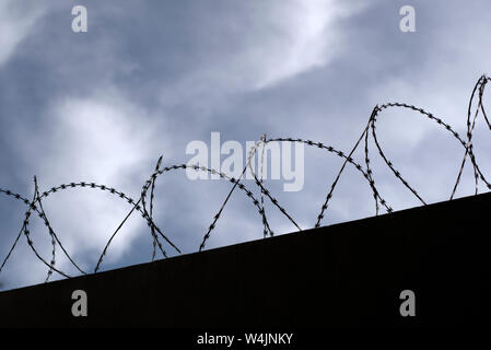 Silhouette von Concertina wire Perimeter an einer Wand Stockfoto