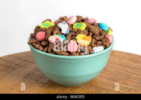 Mit Schokoladegeschmack marshmallow Müsli in eine blaue Schale auf einem Holz und weißem Hintergrund Stockfoto