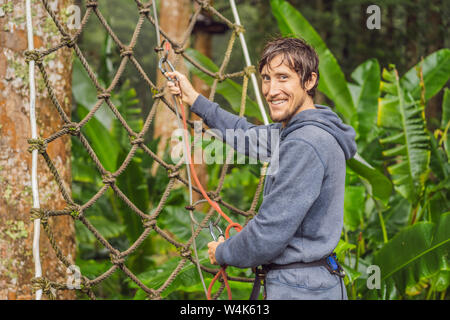 Die jungen Männer in einem Hochseilgarten auf dem Holz Hintergrund Stockfoto
