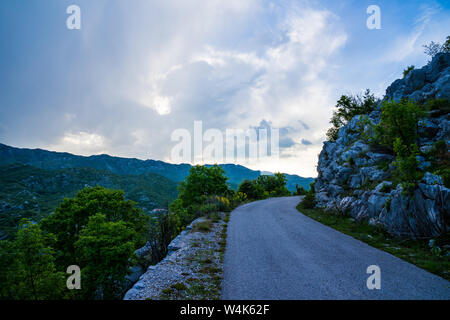 Montenegro, abenteuerliche scenic Mountain Road neben den felsigen Klippen mit endlos weiten Blick über grüne Natur Landschaft von Tal in der Nähe von ostrog bei Sonnenuntergang Stockfoto
