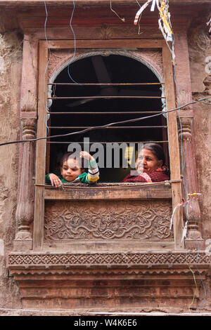 Bikaner, Indien - 11. Februar 2019: Indische Frau mit Kind in Holz geschnitzte Fenster in der Altstadt von Bikaner. Rajasthan Stockfoto