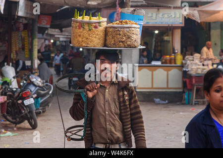 Bikaner, Indien - 11. Februar 2019: Man Snacks, die auf seinem Kopf für den Verkauf auf dem Markt in Bikaner. Rajasthan Stockfoto