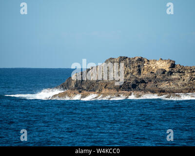 Wellen stürzen über Felsen am Rand einer Insel, blaues Meer und Himmel, Blick vom Coffs Harbour Stockfoto