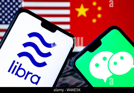 Facebook Waage und WeChat Logos auf den Smartphones und verschwommenes Flaggen der USA und China auf dem Hintergrund. Konzeptionelle Foto. Stockfoto