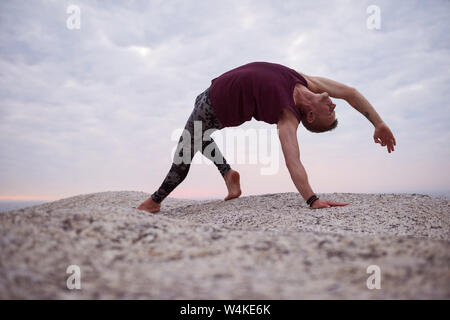 Mann tun die wilde Sache Pose auf Felsen in der Dämmerung Stockfoto