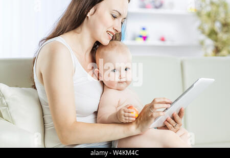 Glückliche Mutter ein Jahr altes Baby Holding auf seinen Händen und zeigt ihr Bild auf digital Tablet Stockfoto