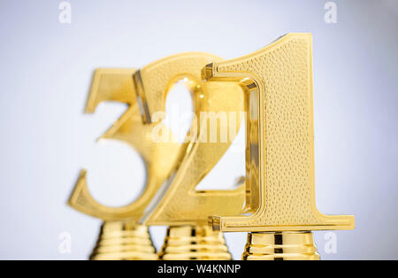Gold Trophäen für die Sieger und die 2. und 3. platzierten Läufer oben in einem rückläufigen diagonale Linie auf weißem in der Form der Zahlen eins, zwei und drei Stockfoto