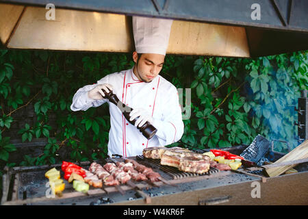 Der Küchenchef bereitet das Fleisch auf dem Grill. Stockfoto