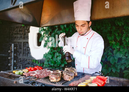 Der Küchenchef bereitet das Fleisch auf dem Grill. Stockfoto