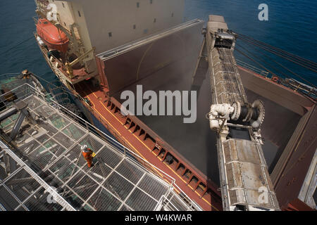 Bergbau, Verwaltung und Transport von Titanmineralsanden. Beladung von Mineralsand-Fracht über den Umschlag von Barge Boom in den Besitz von Bulk Carrier auf See. Stockfoto