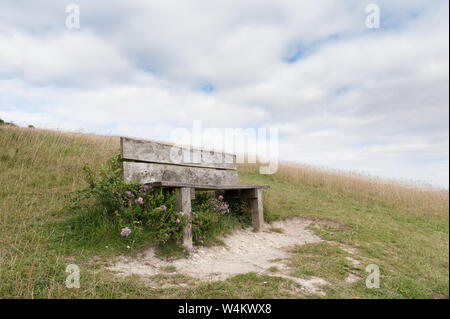 Alte knorrige gebleicht Holzsitz Parkbank, auf einem Hügel in Kreide Grünland nach Süden in Richtung Northdowns, Sevenoaks, Yalding, mit spektakulären Tal Stockfoto