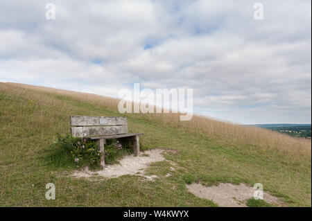 Alte knorrige gebleicht Holzsitz Parkbank, auf einem Hügel in Kreide Grünland nach Süden in Richtung Northdowns, Sevenoaks, Yalding, mit spektakulären Tal Stockfoto