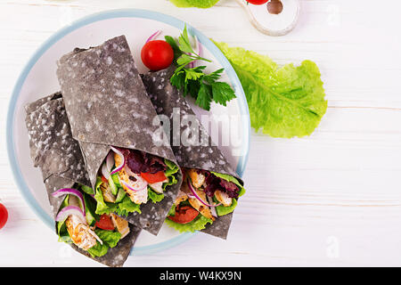 Tortilla mit Tinte Tintenfisch Wraps mit Hähnchen und Gemüse auf weißem Hintergrund. Chicken burrito, mexikanisches Essen. Ansicht von oben Stockfoto