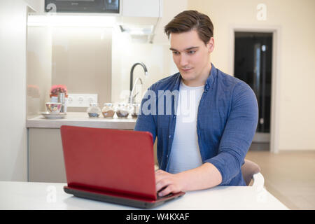 Jungen gutaussehenden Mann in seinen Laptop von zu Hause freiberuflich Stockfoto