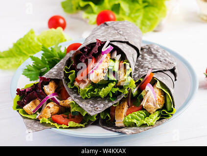 Tortilla mit Tinte Tintenfisch Wraps mit Hähnchen und Gemüse auf weißem Hintergrund. Chicken burrito, mexikanisches Essen. Stockfoto