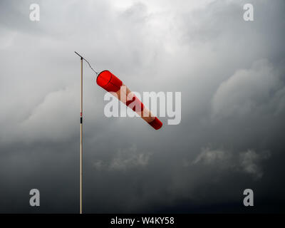 Windsack Rot auf Schwarz stürmischen Himmel. Schlechtes Wetter, meteorologischen Windanzeiger. Stockfoto