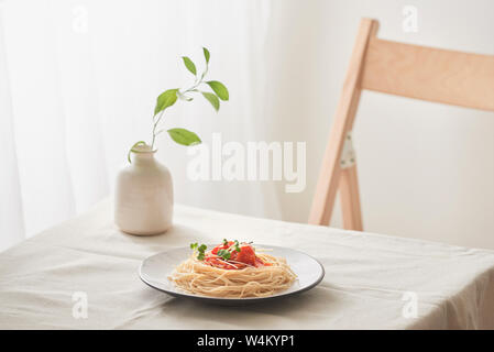 Handgemachte Pasta mit Ragout Soße auf Platte auf Vintage White Tisch mit Sieb und Blumen Stockfoto