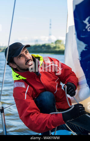 Des Menschen Hand mit Boot Seil. Yachtsman Mauren seinen Motor Boot am Steg. Nahaufnahme, Hände und Bug des Bootes. Stockfoto